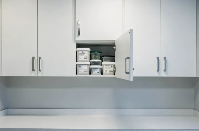 Rangements fermés en meubles hauts blancs avec poignées métalliques dans une salle de pause pour maintenir l'ordre et éviter le désordre